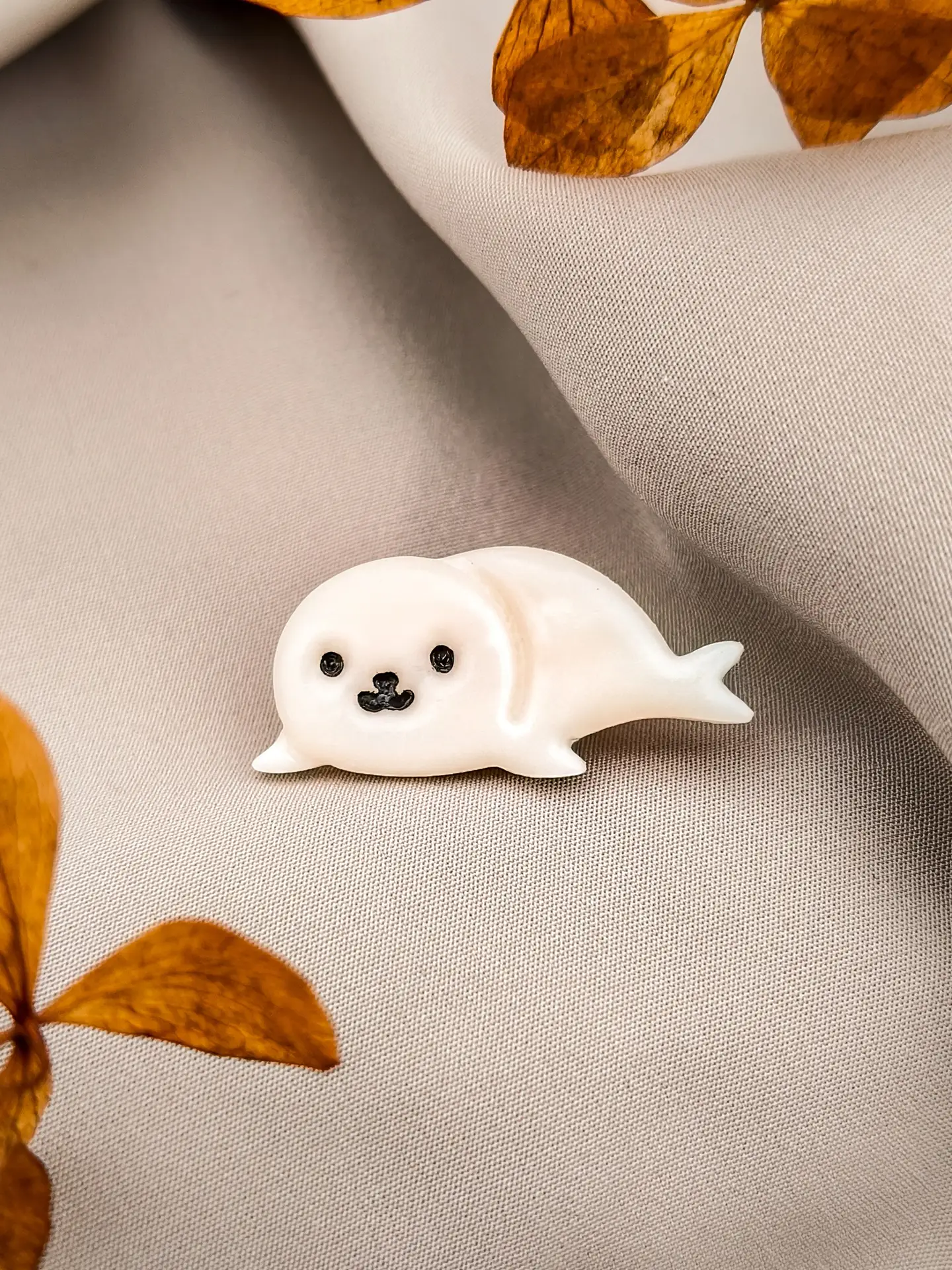 Ręcznie robiony pin z foką. Biżuteria wykonana z gliny polimerowej w kształcie białej uroczej foczki.